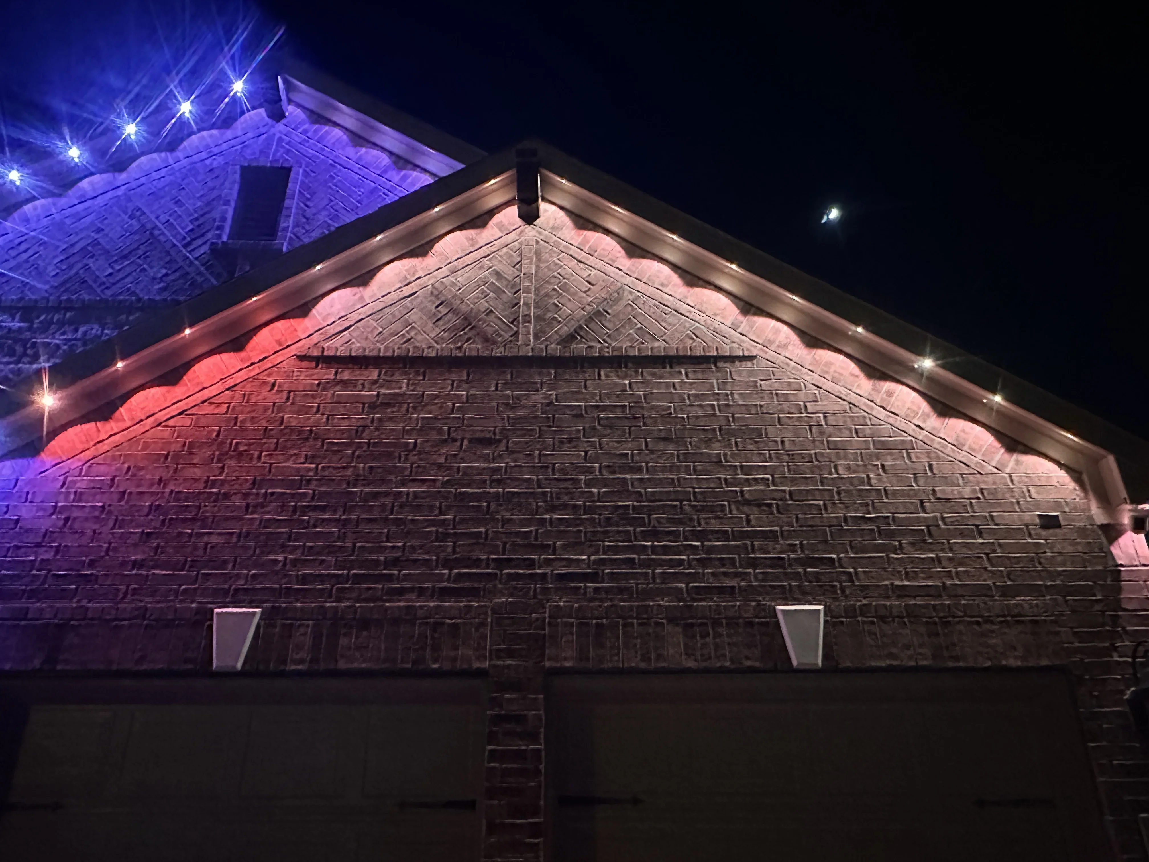 Brick gable facade with warm and cool LED accent lighting along roofline and soffit at night