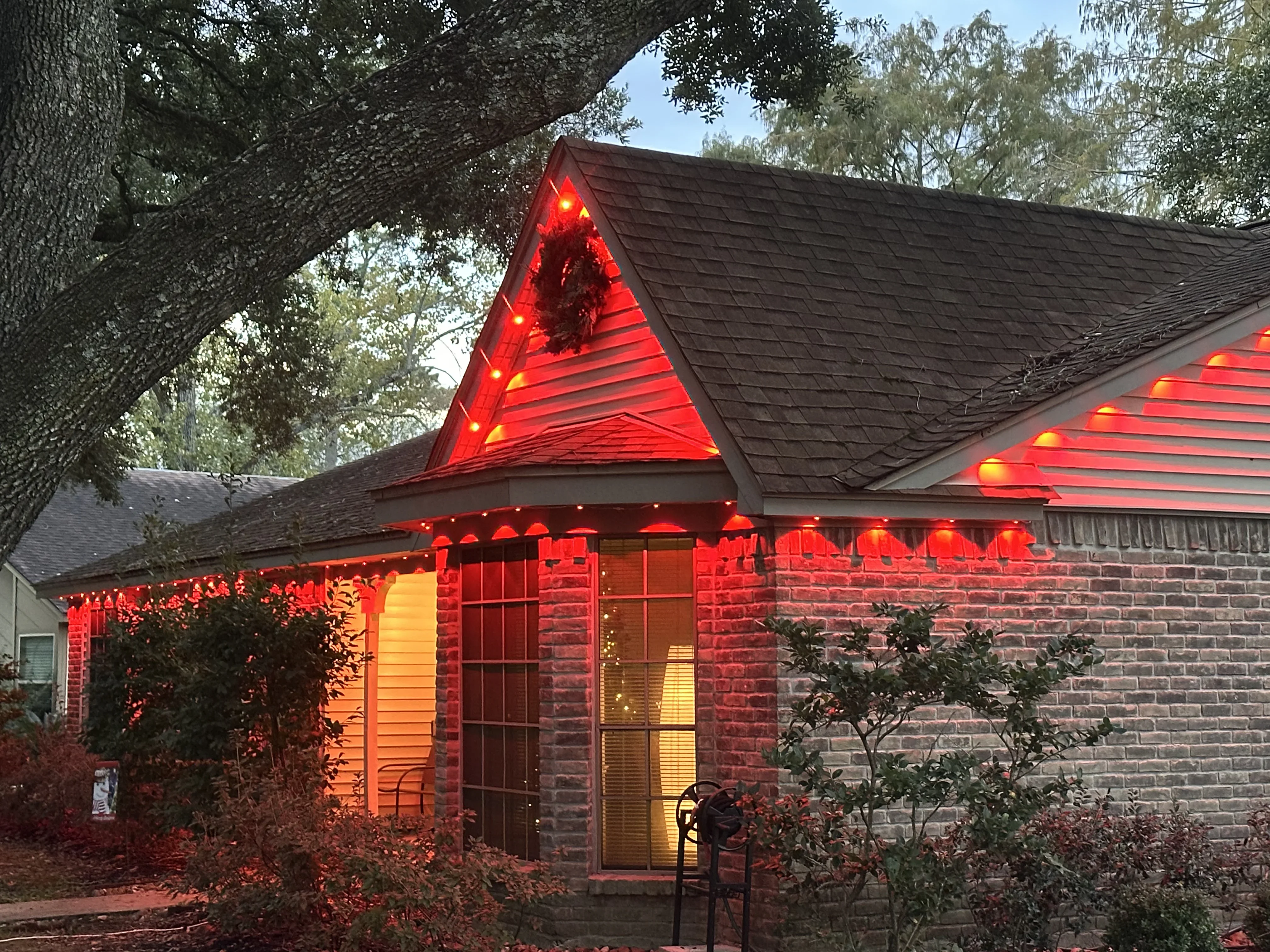 Brick home with LED roofline and gable lighting, warm white lights outlining roof edges and peak