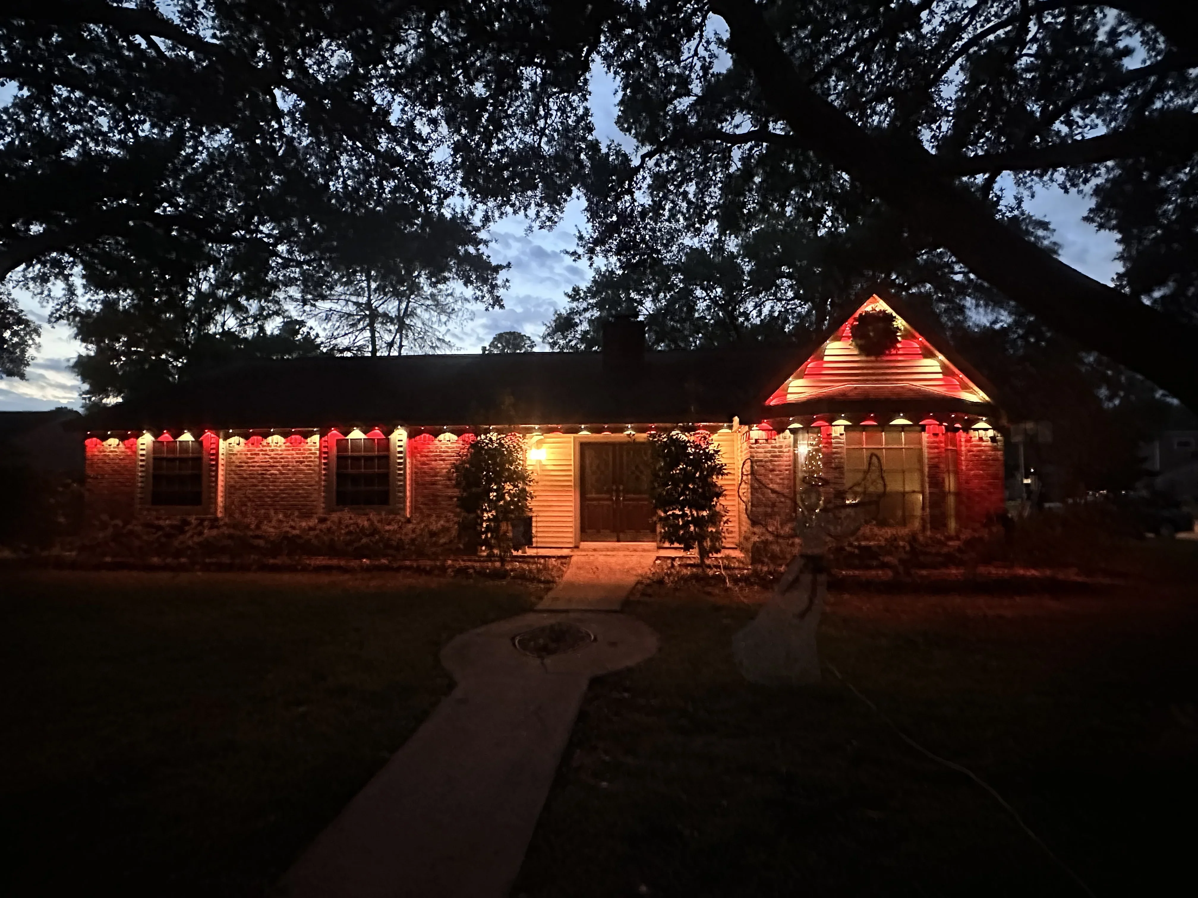 Brick home with warm LED accent lighting on roofline, soffit, and gable peak at dusk