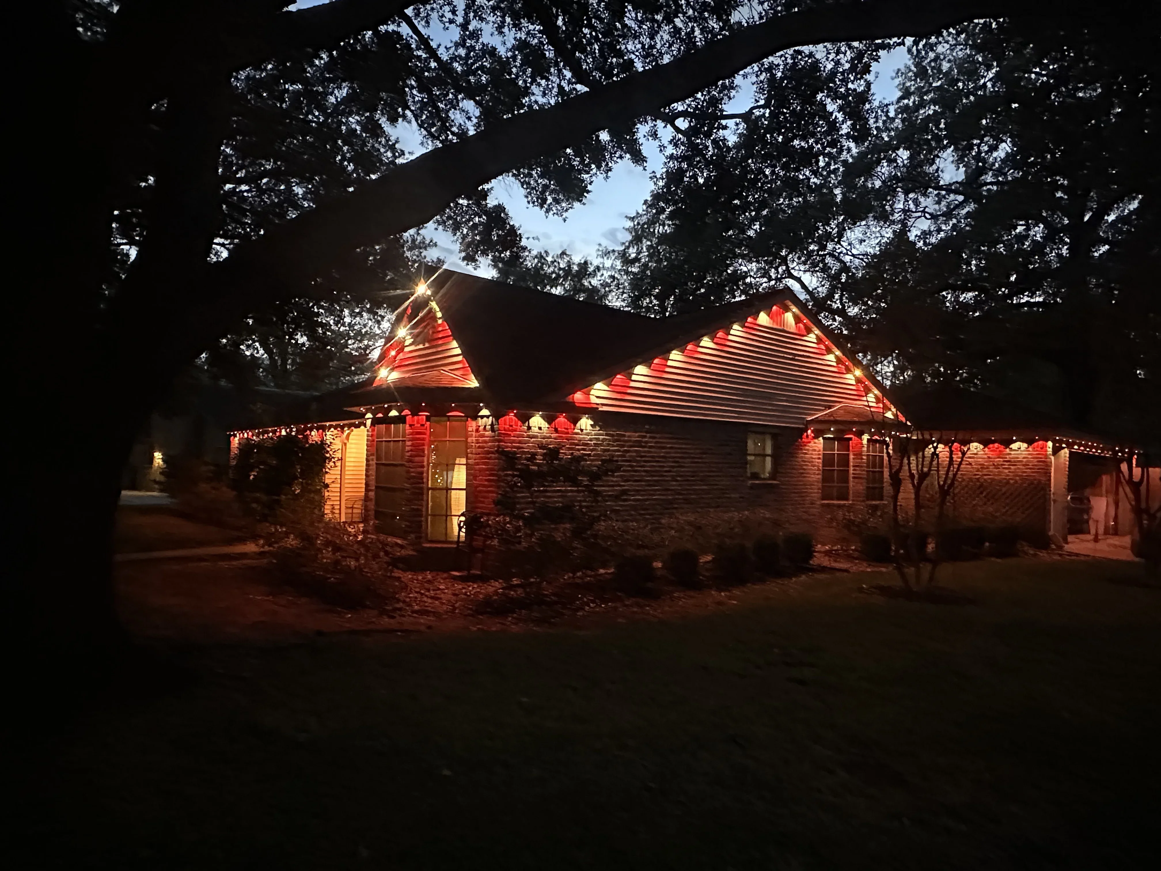 Brick home with warm LED accent lighting on roofline and gable peaks at night