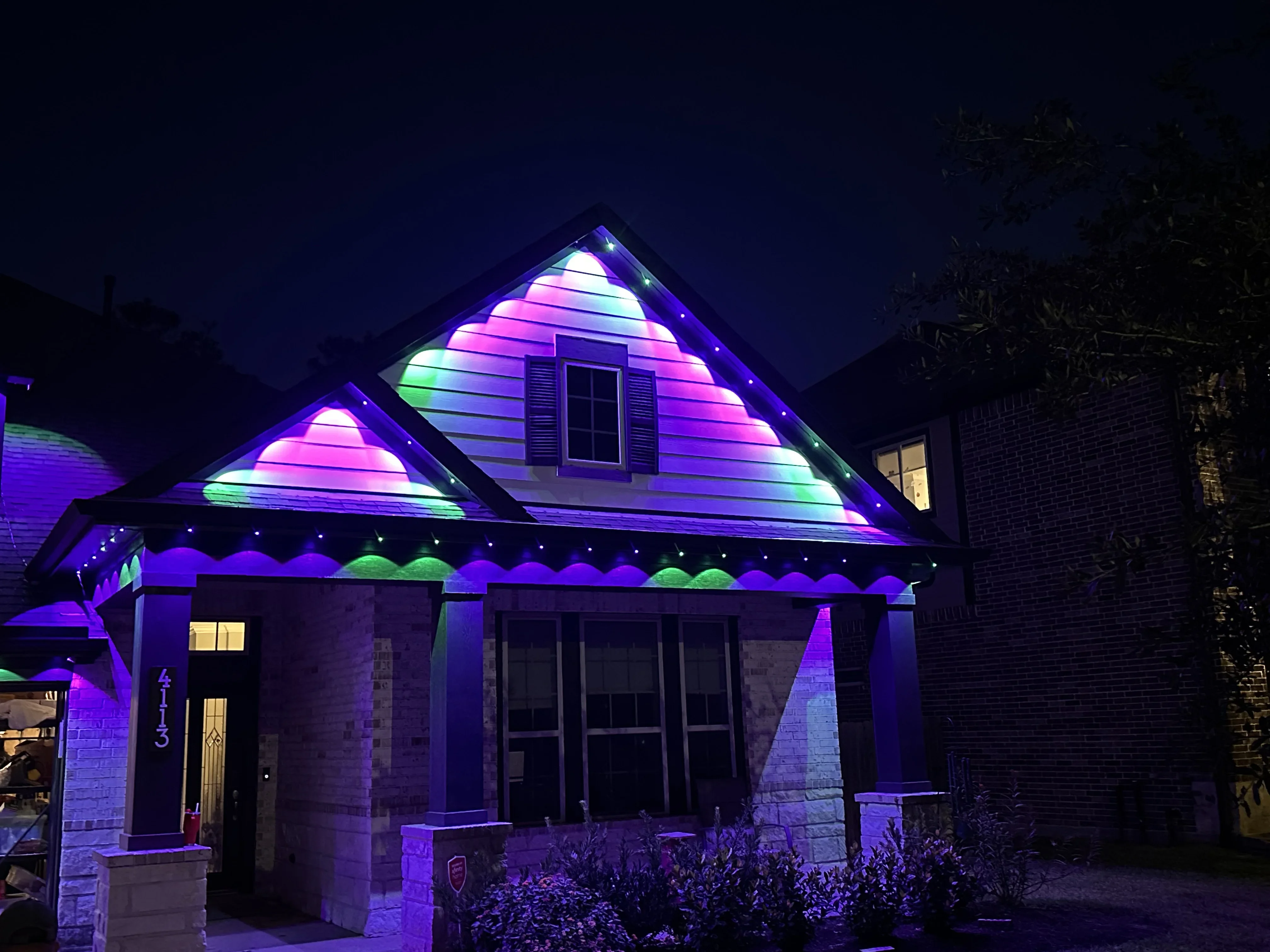 RGB LED lighting on residential gable and soffit with purple, pink, and green color effects
