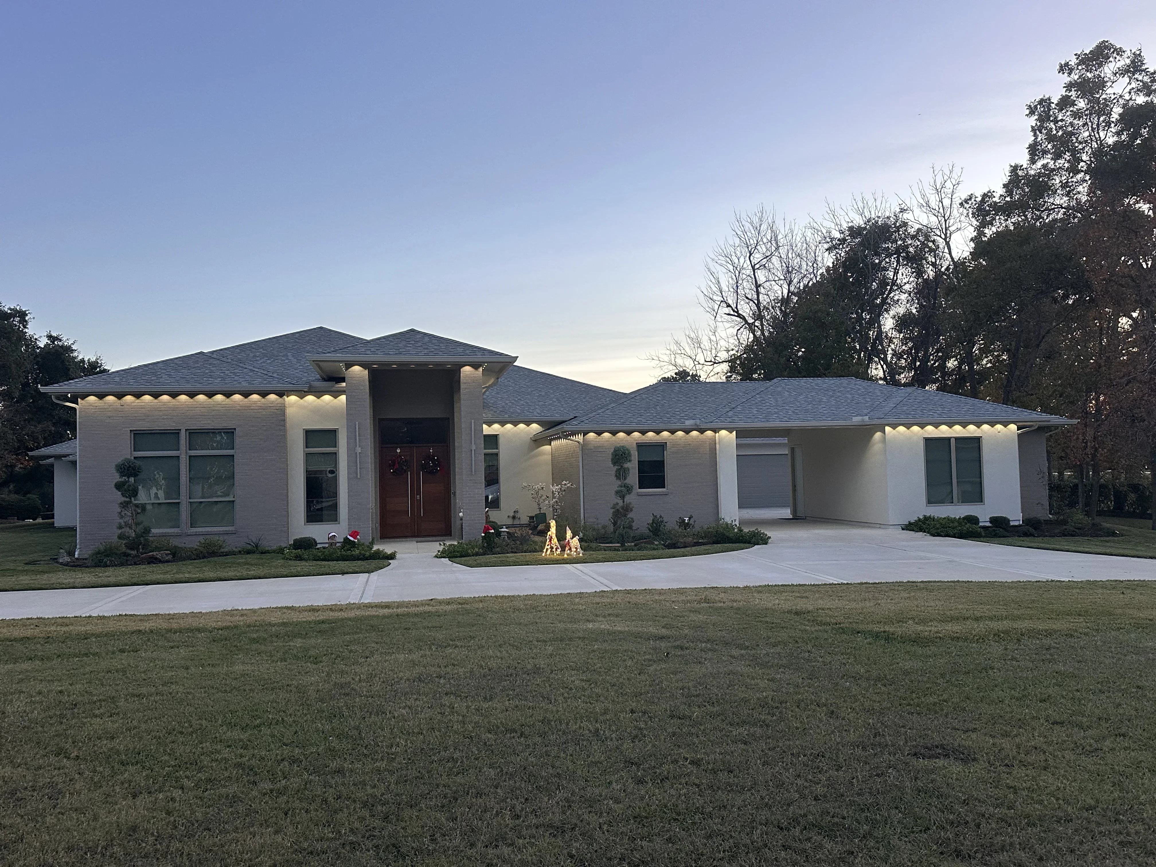White brick modern home with warm LED soffit and accent lighting along roofline and entry