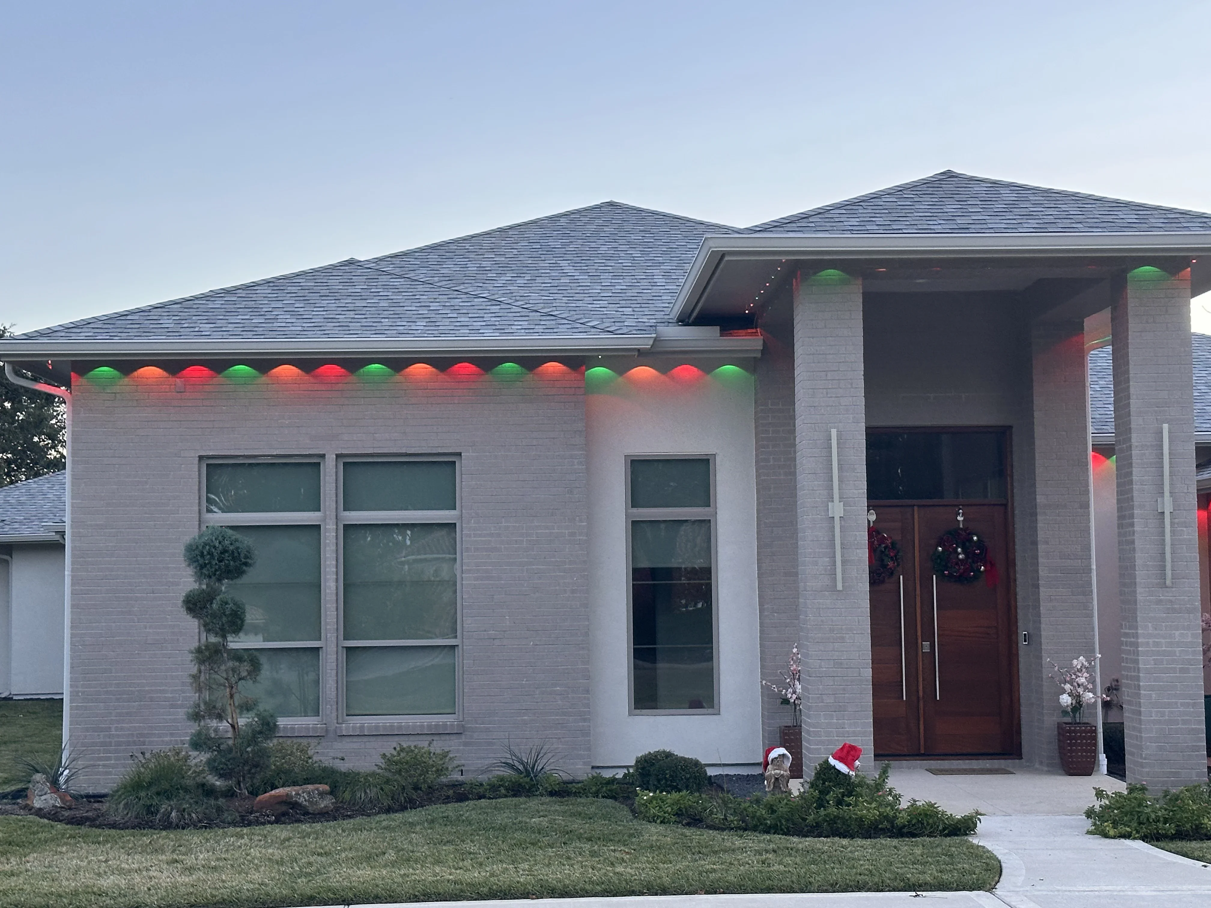 LED accent lights in red, orange, and green installed along roofline of modern brick home