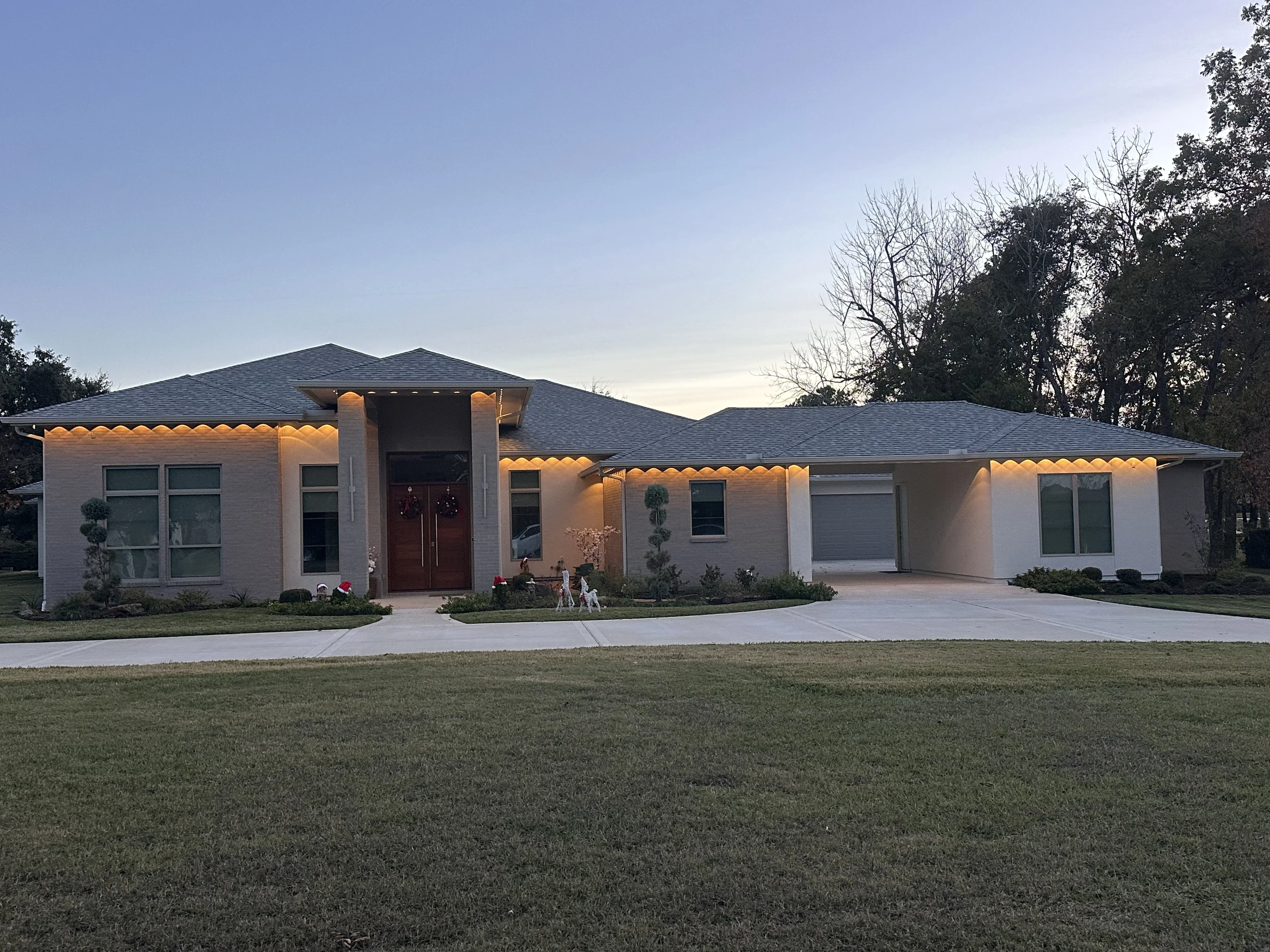 White brick contemporary home with warm accent lighting along roofline and soffit at dusk