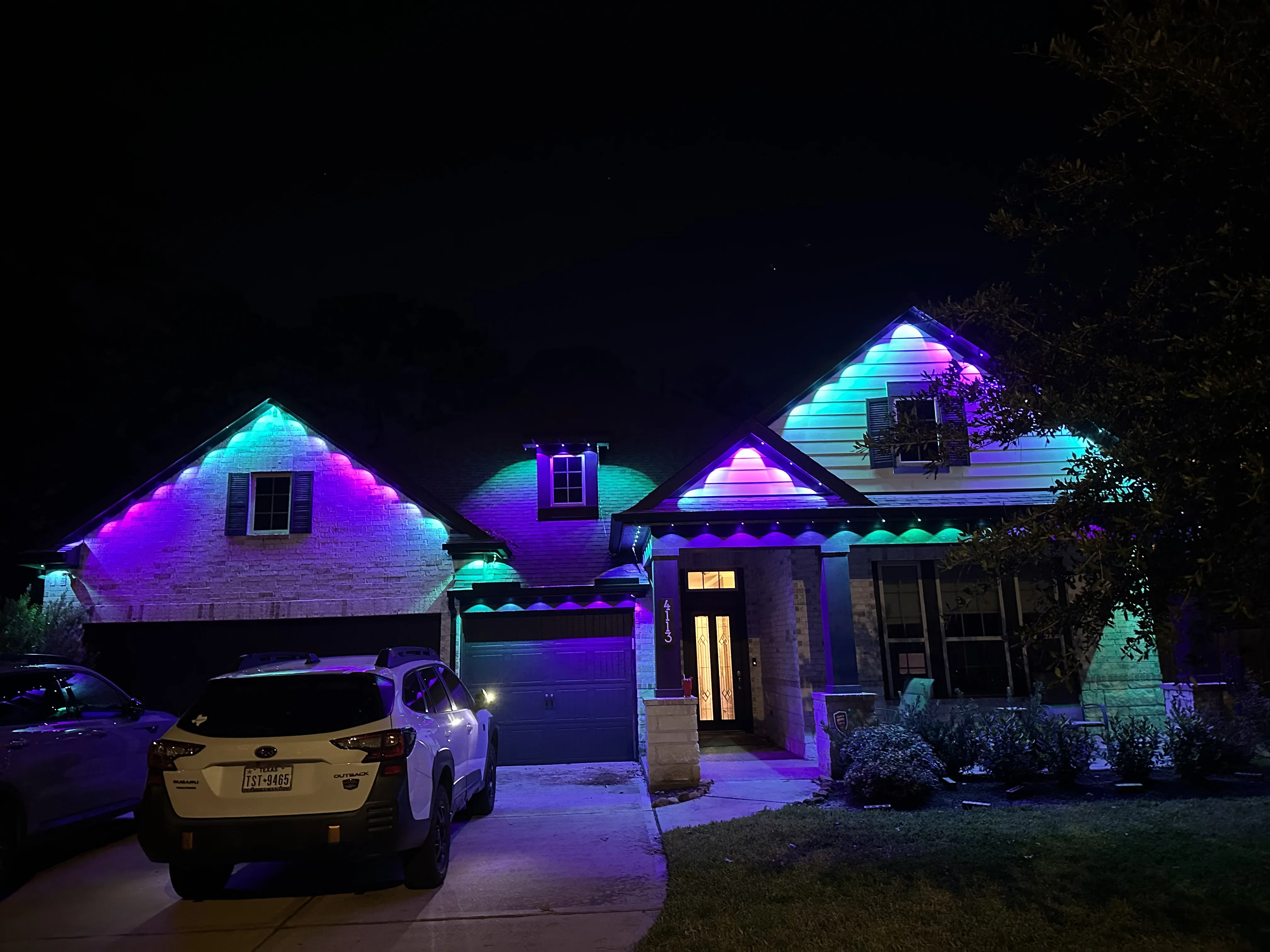 Residential home with RGB LED architectural lighting on rooflines and gables in cyan and magenta colors