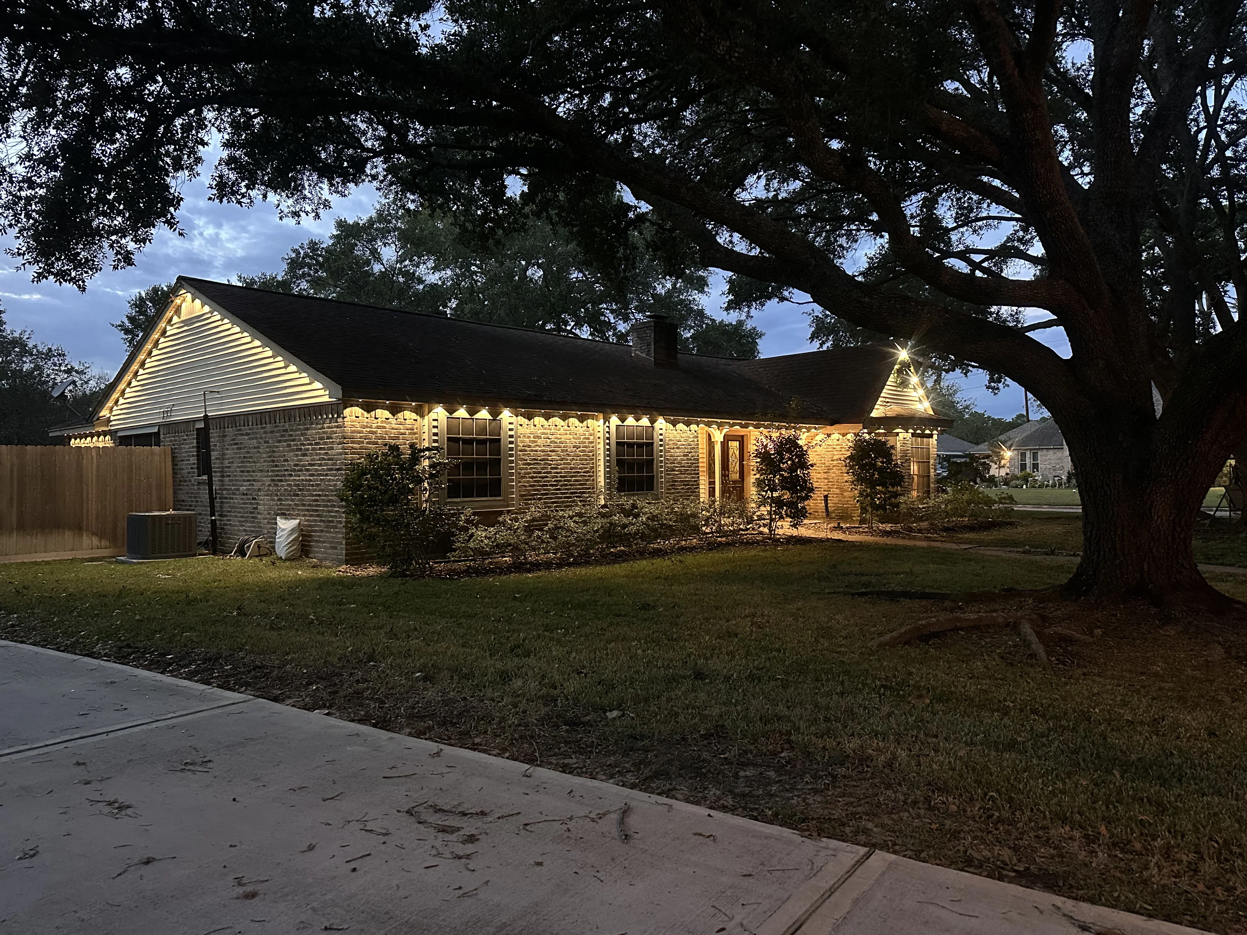 Brick home with warm exterior uplighting, soffit lights, and entryway accent lighting at dusk