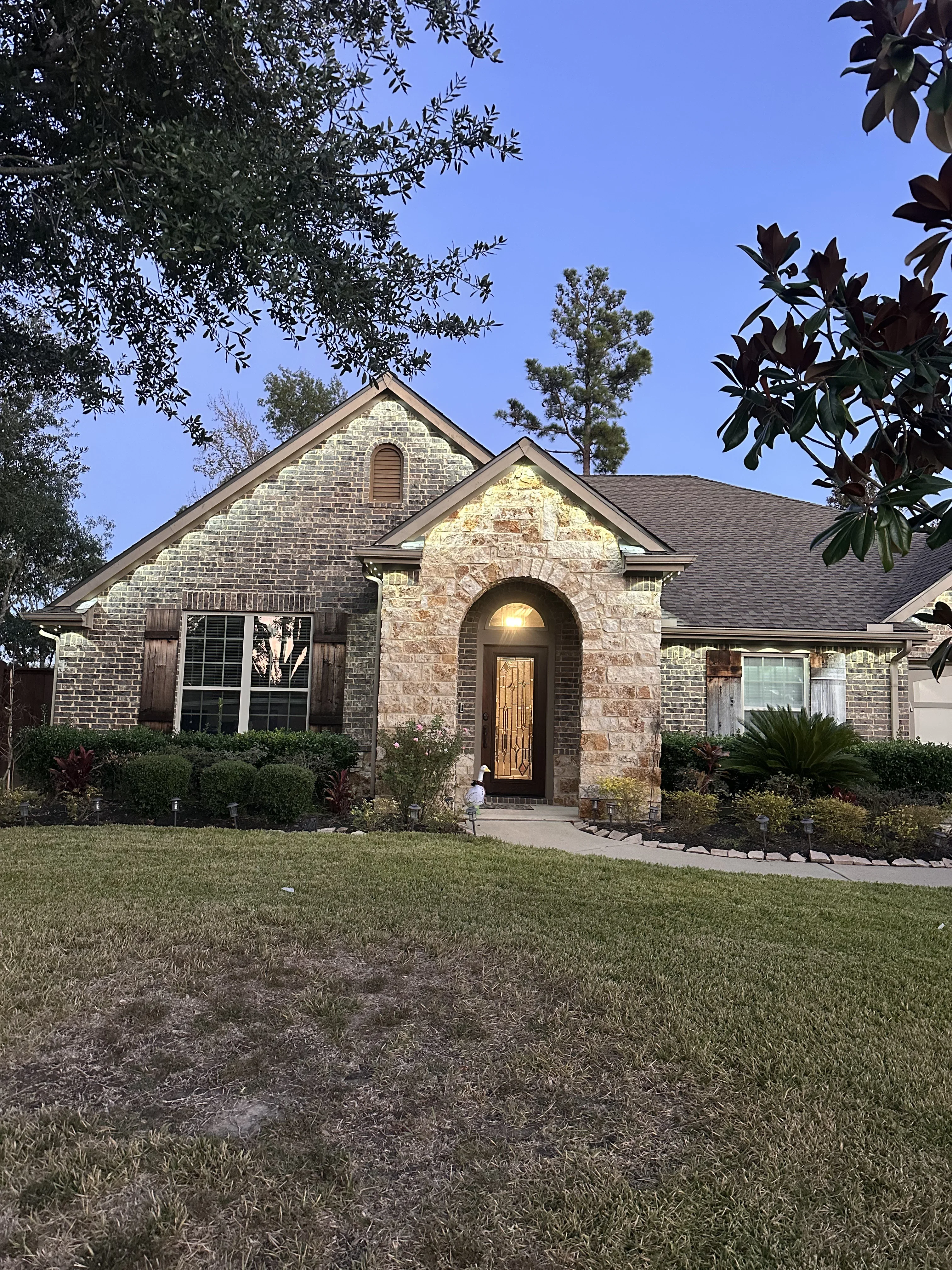 Brick and stone home exterior with warm accent lighting on arched entryway and facade