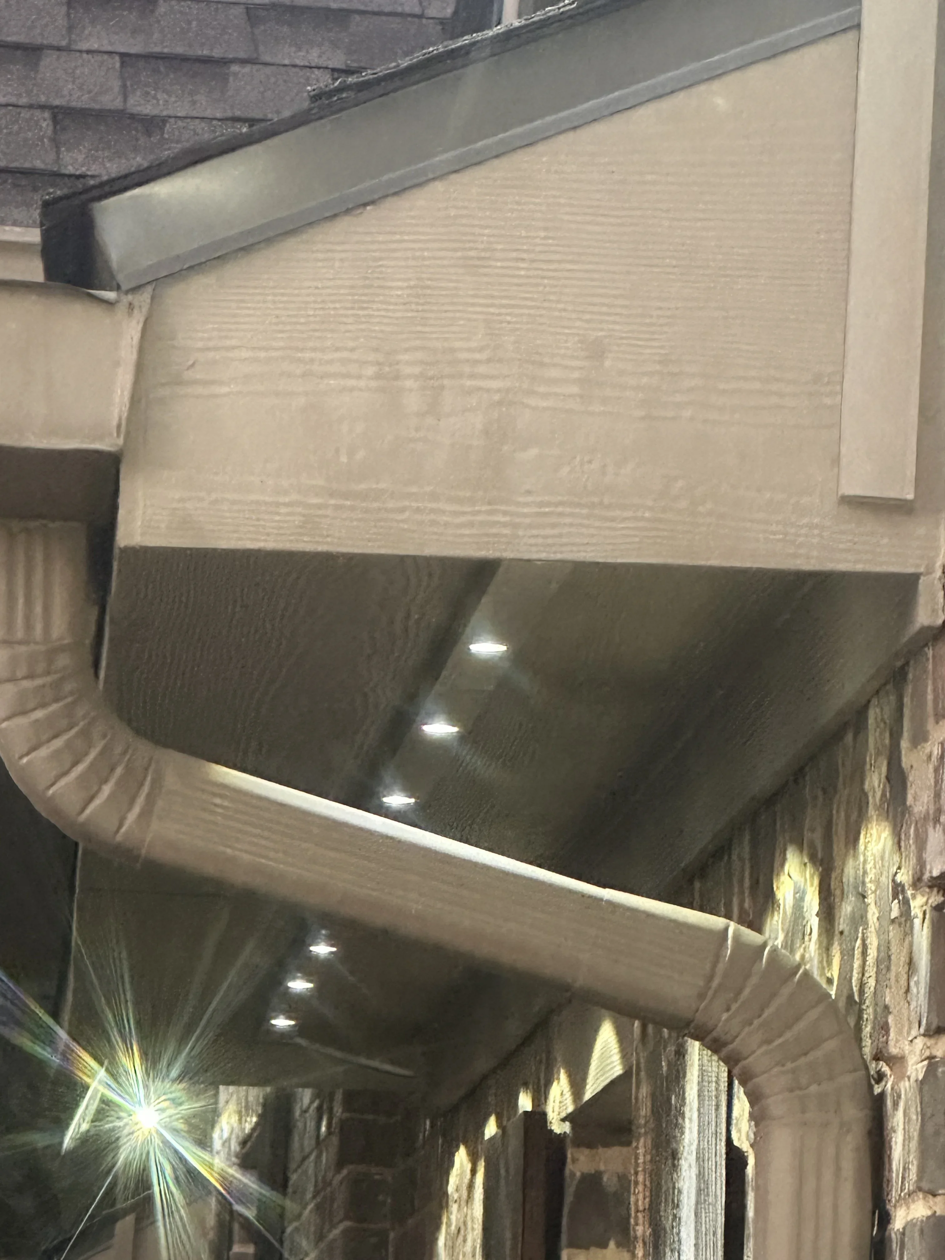 Recessed LED lights installed in cream and dark gray soffit with metal fascia trim