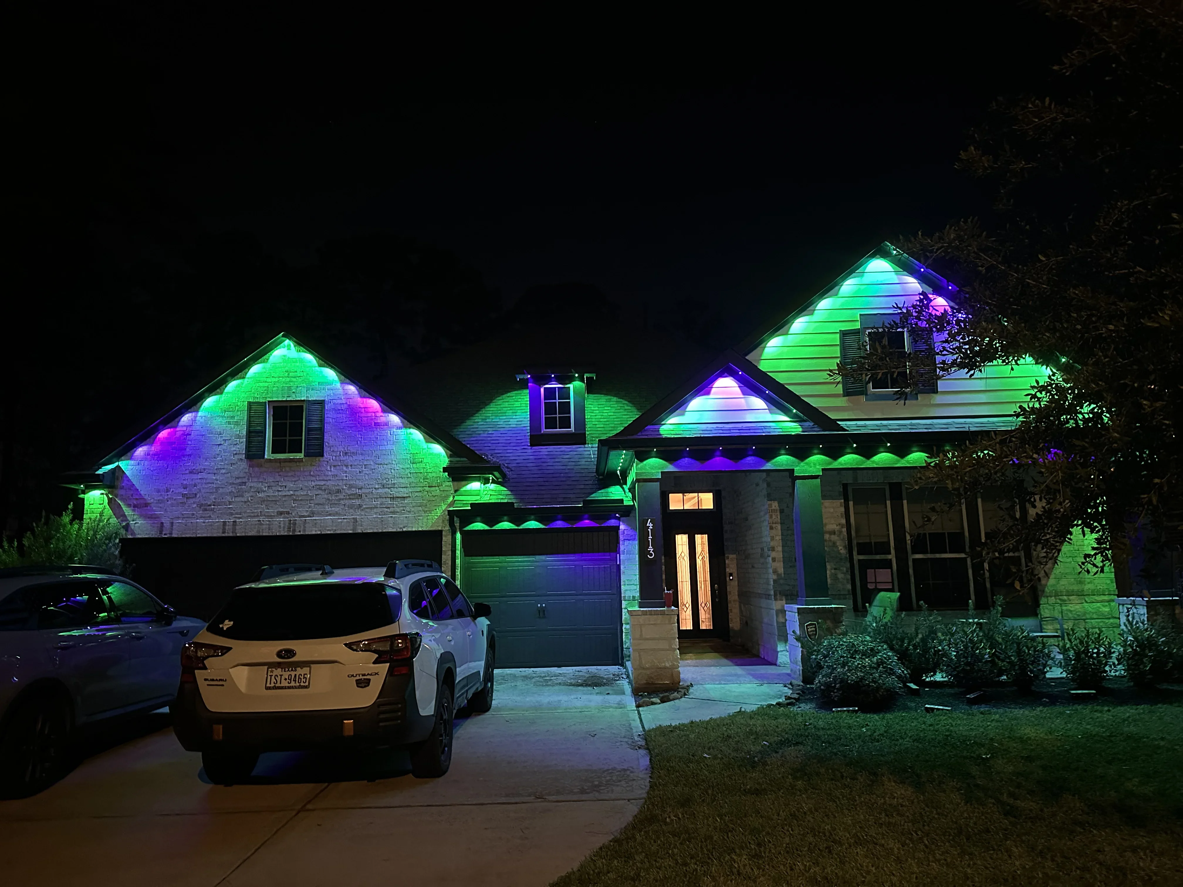 Home exterior with green and purple RGB LED lighting on rooflines and gables at night