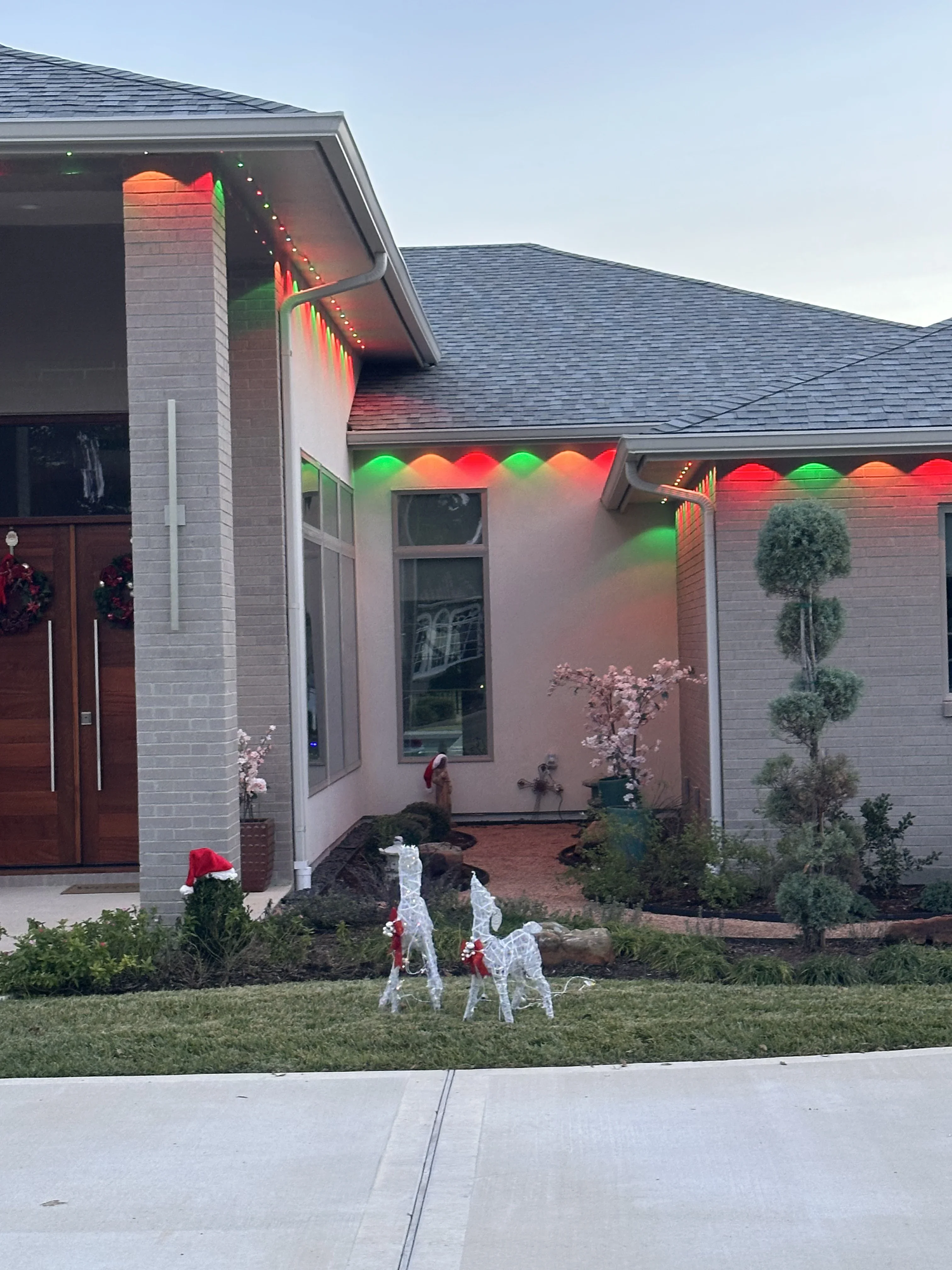 Multicolor LED roofline and soffit lighting with red, green, and orange bulbs on brick home exterior