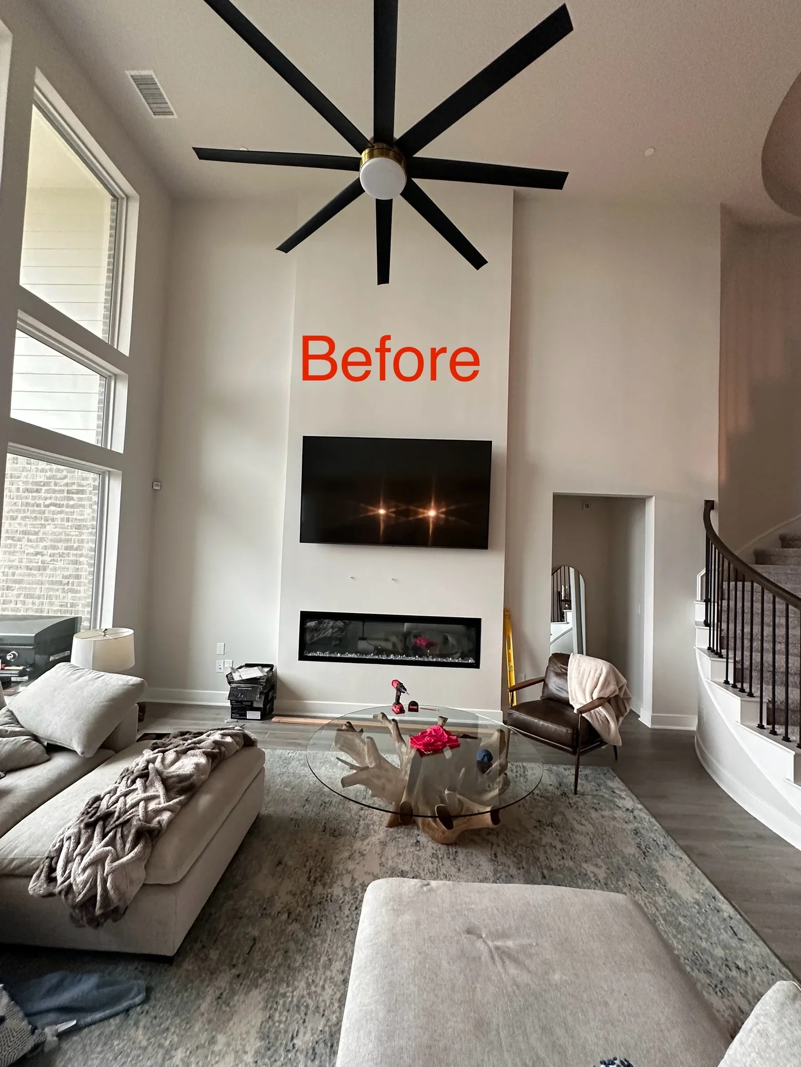 Black eight-blade ceiling fan with light fixture mounted on white ceiling in open living room