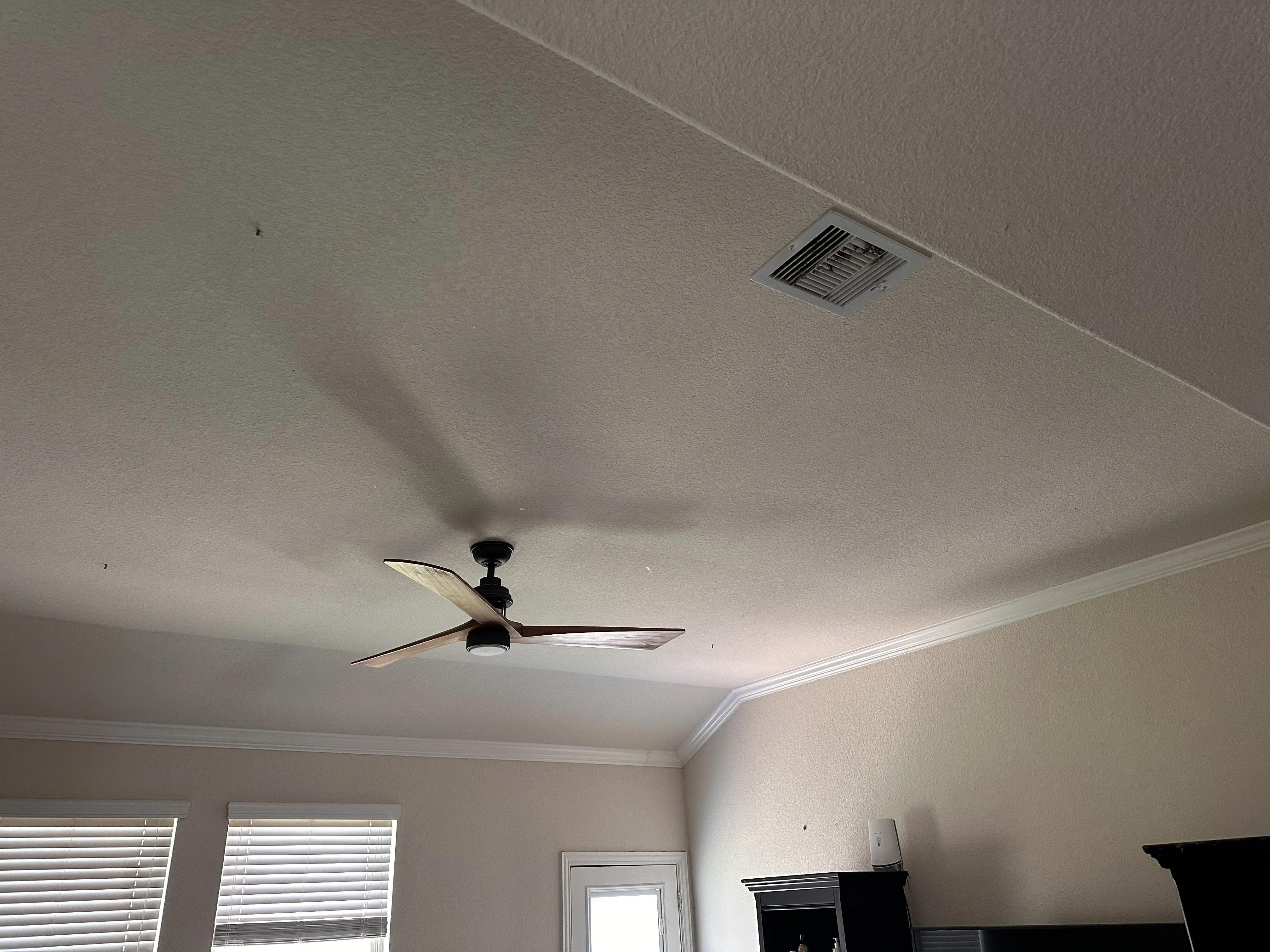 Black ceiling fan with recessed lighting and ventilation duct in white drywall ceiling