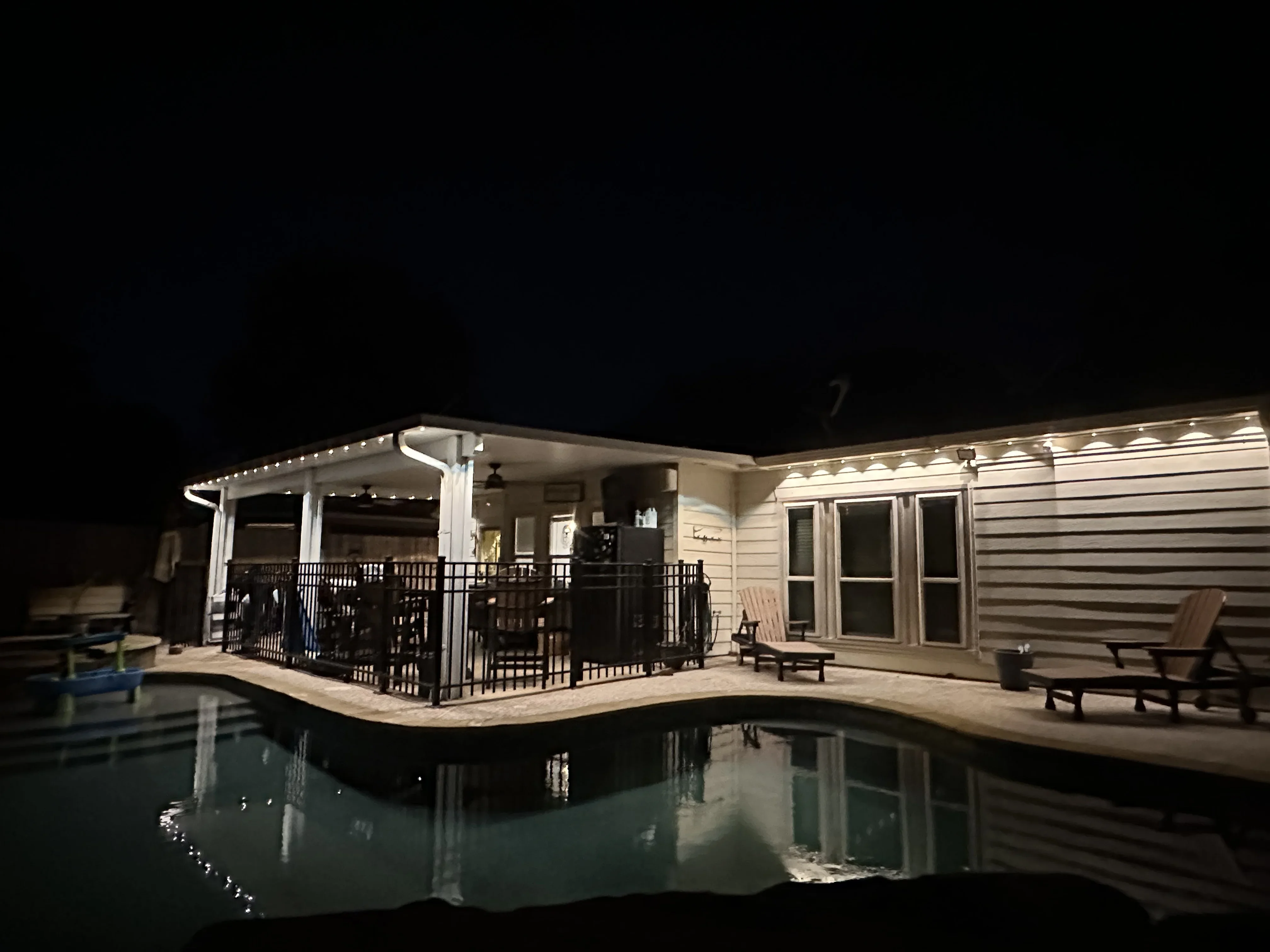 LED-lit pergola and deck with recessed soffit lighting and landscape accents around pool area at night