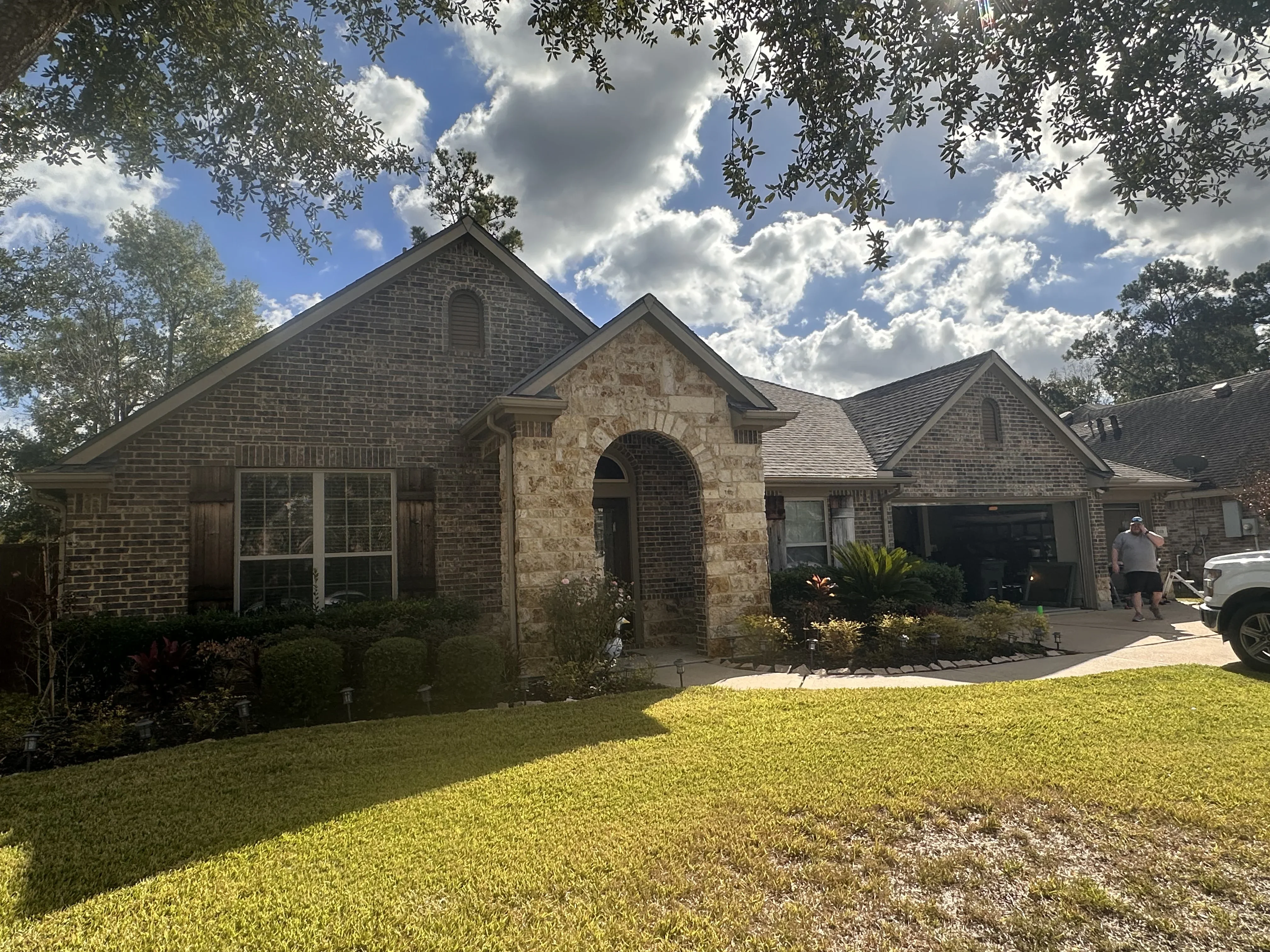 Brick and stone home with exterior accent lighting on arched entry and landscape lighting
